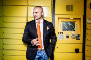rafał brzoska standing in front of yellow parcel locker