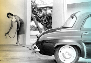 View of a woman charging the vintage electric car