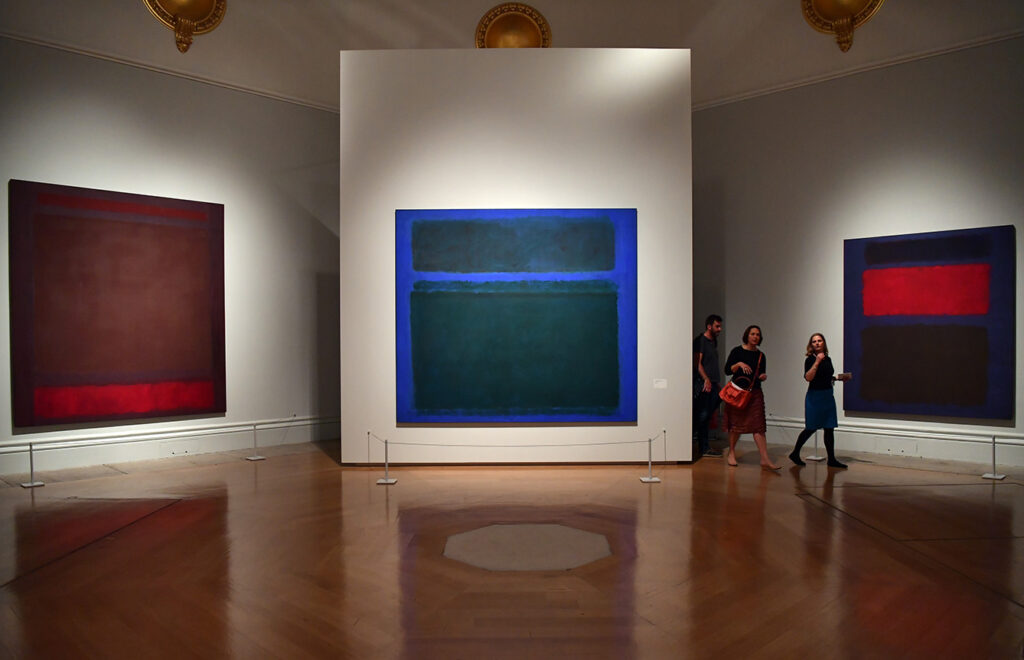 Visitors in gallery walk past paintings by artist Mark Rothko