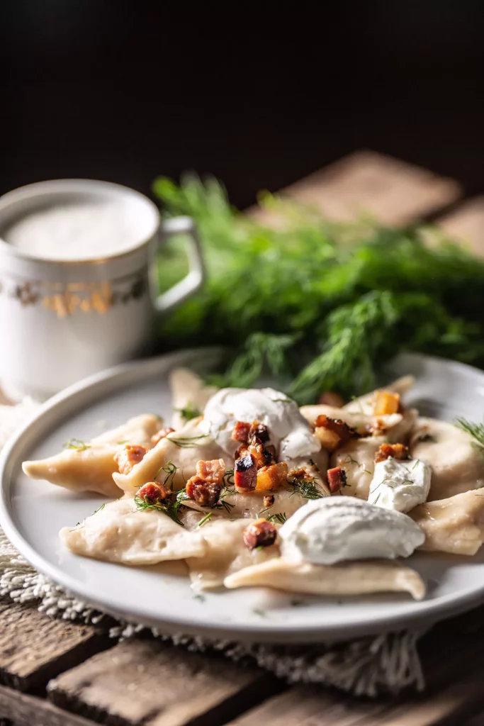 Filled pirohy dish served with fried bacon, fresh dill, sour cream and a cup of milk