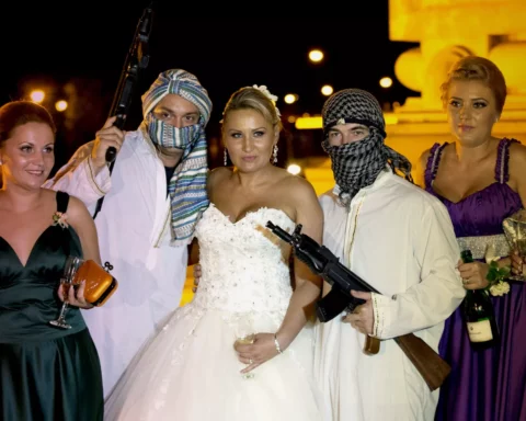 Romanian bride poses with mock kidnappers holding a toy weapons at the Triumph Arch in Bucharest Romania