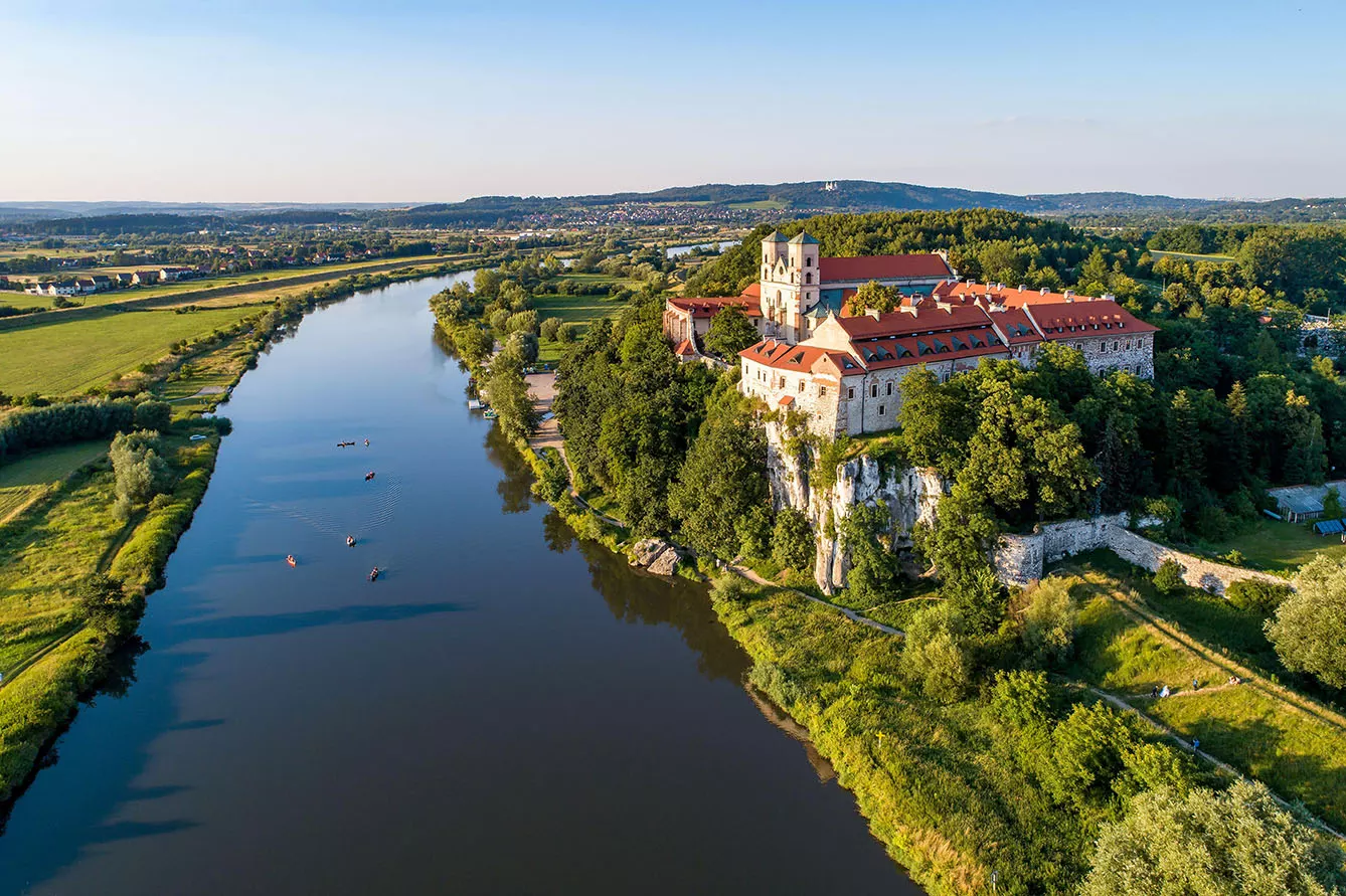 Tyniec near Krakow, Poland. Benedictine abbey, monastery and church on the rocky cliff and Vistula river with canoes and kayaks. Aerial view at sunset
