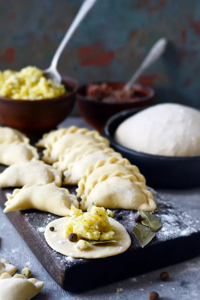 Dumplings with potatoes and cheese with herbs on a blue background