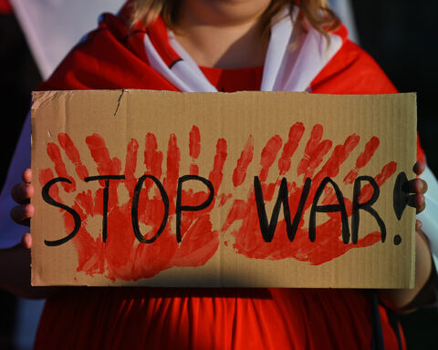 A protester holding a placard with words 'Stop War!