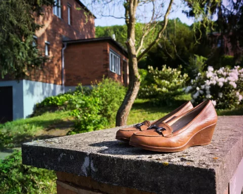 Old vintage shoes with typified red brick family Bata house in background, Zlin, Moravia, Czech Republic, sunny summer day