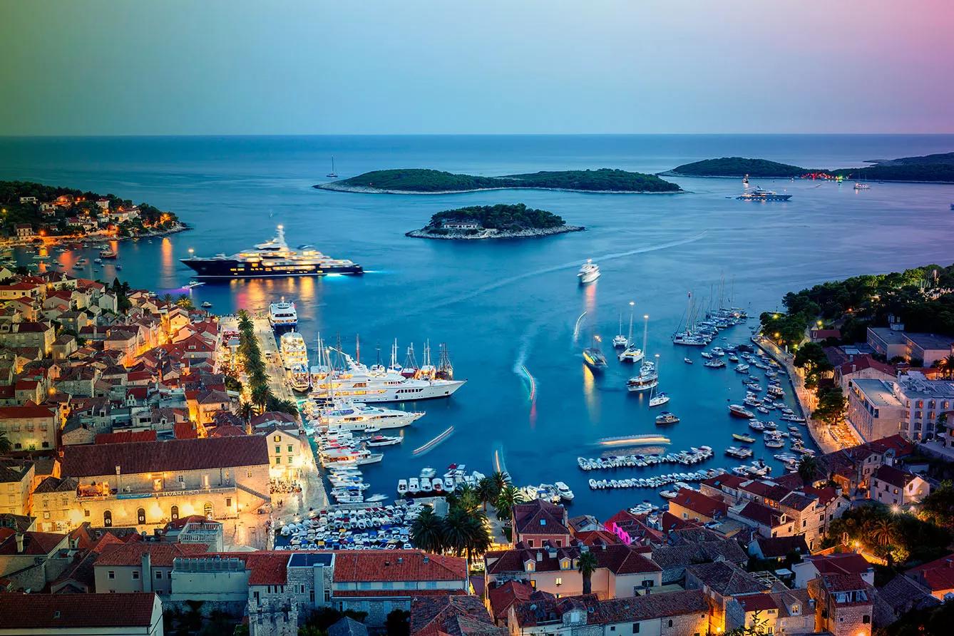 iew of the illuminated old town Hvar and the harbor with Pakleni Islands at dusk