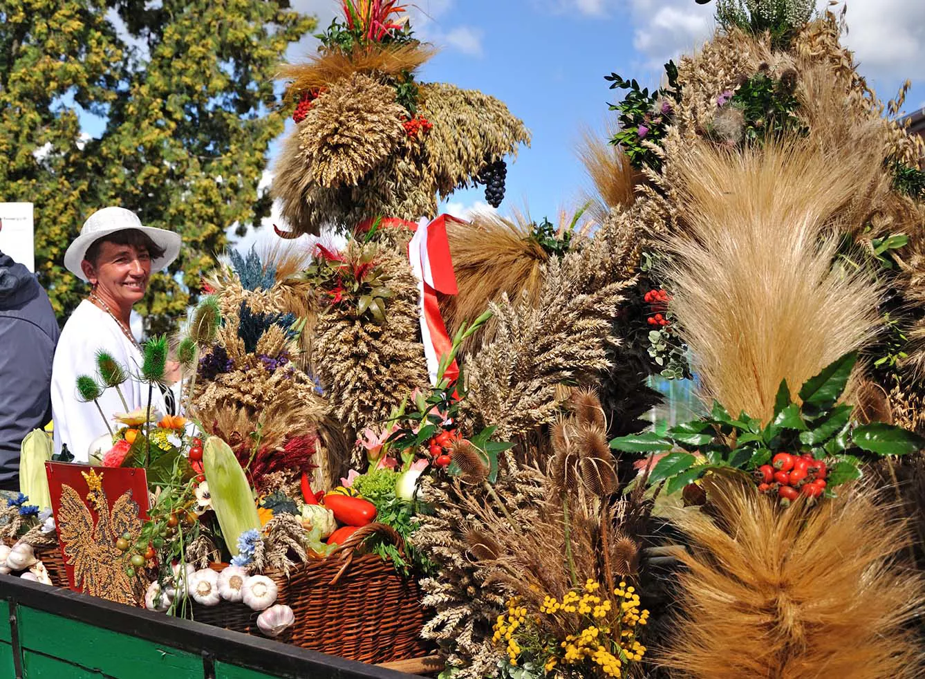 Polish harvest festival - Green cart full of harvest garlands with smiling woman in white dress and white hat