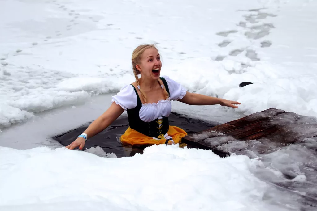 woman wearing a costume takes a dip in cold water during the Sauna Marathon