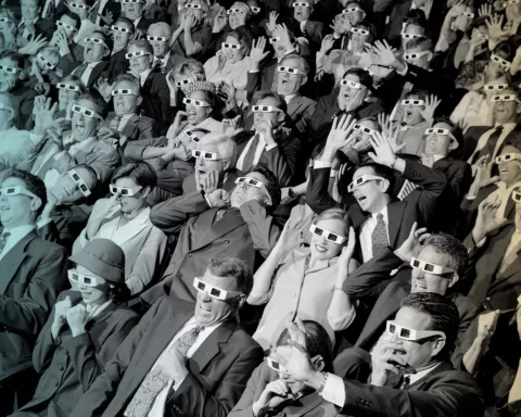 group of spectators sitting in a movie theater wearing 3-D glasses