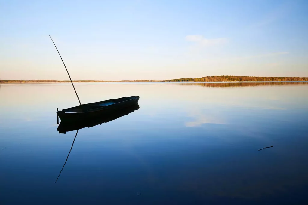 solitary fisherman boat on the fish pond Rožmberk during the sunset