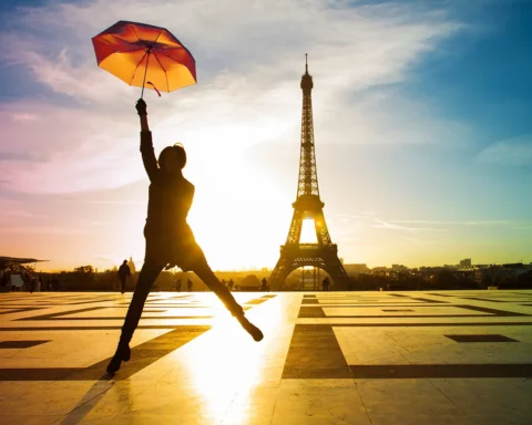 Young attractive woman with bright umbrella. Amazing sunrise on trocadero place and eiffel tower in Paris