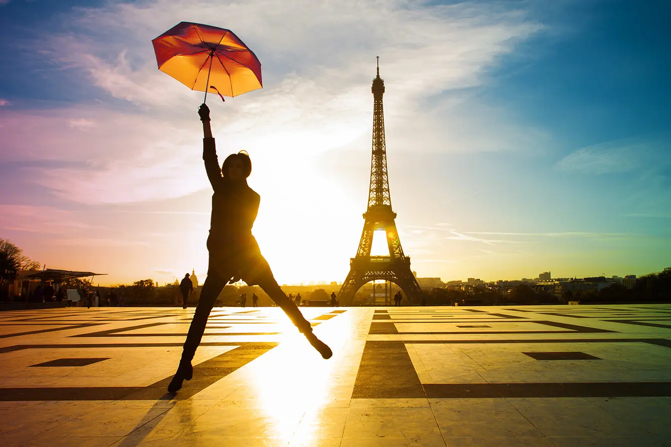 Young attractive woman with bright umbrella. Amazing sunrise on trocadero place and eiffel tower in Paris