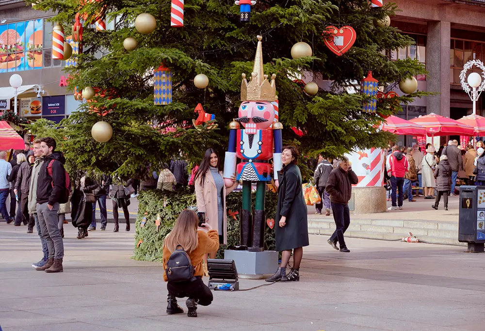 Two lovely ladies posing next to one of the Nutcracker statue next to large Christmas tree in centre square at Advent Market in Zagreb, Croatia