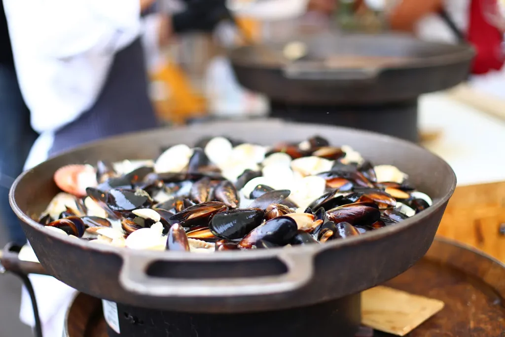 Mussels cooked by a cook in a huge frying pan at a street fair in Slovenia