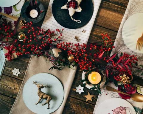Holiday Gold place setting, funny Christmas table with ornaments and natural berries on wooden table