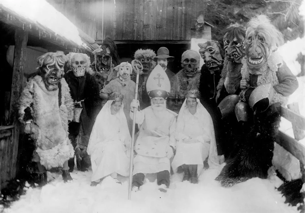 Saint Nicholas and his helpers with wooden-carved masks in Matrei in East Tyrol. Old photograph from 1935