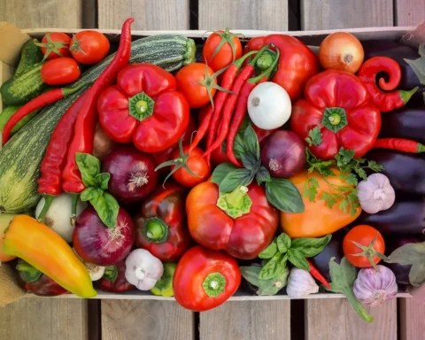 Harvest fresh vegetables in a box on a wooden background, top view