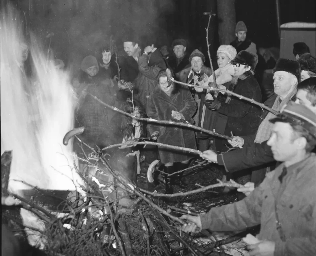 winter sleigh ride in Międzyzdroje. People sit around a fire and roast sausages. Black and white photo from 1970