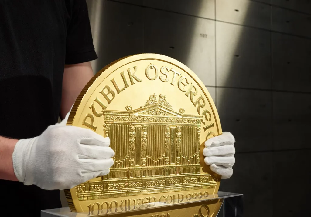 An employee handles a 31 kilogram Vienna Philharmonic gold coin, known as Big Phil, inside the precious metals vault at Pro Aurum KG in Munich