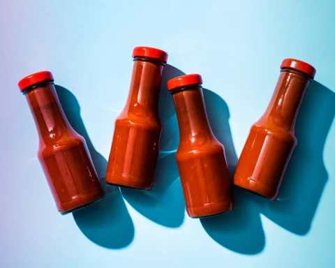 Top view of tomato sauce in bottles with shadow on blue background