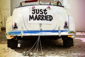 "Just Married" sign and cans attached to convertible car's trunk. Horizontal shot