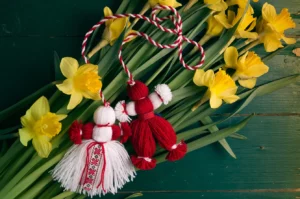 Martenitsa or Martisor on a bouquet of yellow daffodils on a green wooden table top view