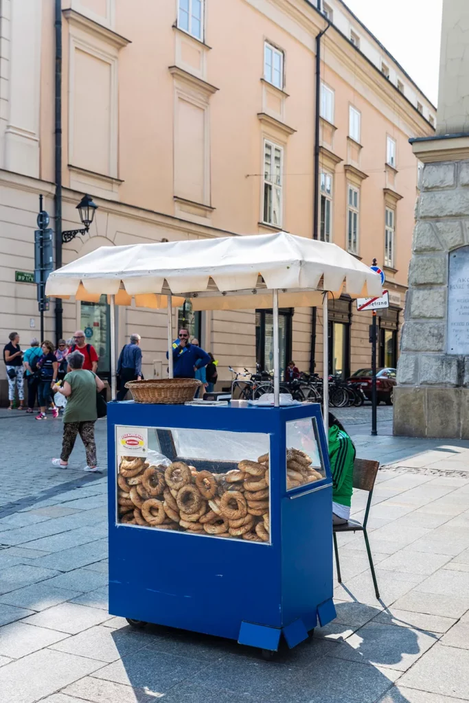 Traditional obwarzanek krakowski, braided ring-shaped bread, in a stall on a street with people around in the old town of Krakow