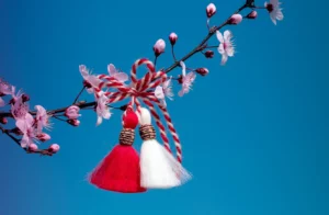 Blossoming tree branch and martisor against the blue sky