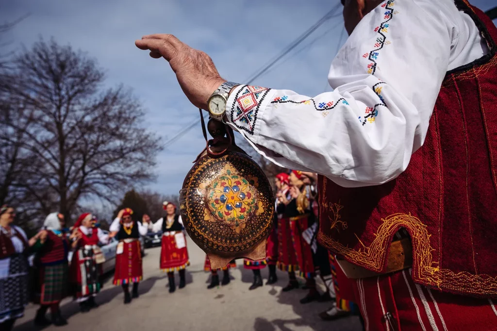 Bulgarians pours a vine with a red wine as dressed with national traditional clothes people play a dance as part of the celebrating of the wine feast called St. Trifon day