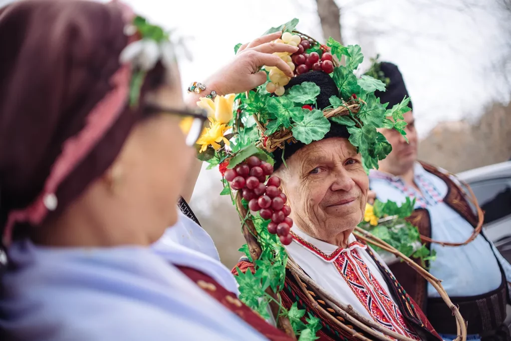 Bulgarians pours a vine with a red wine as dressed with national traditional clothes people play a dance as part of the celebrating of the wine feast called St. Trifon day