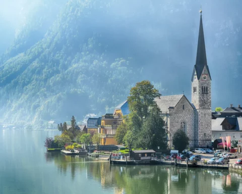 Lake view of Hallstatt village and famous church at summer season in Salzkammergut, Austria