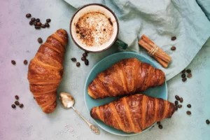 Fresh croissants, together with espresso coffee on a blue background. The view from the top