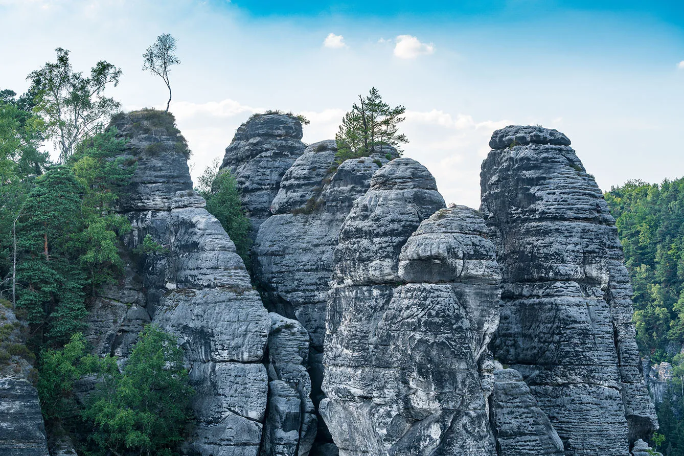 Bad Schandau in Bohemian Switzerland. Bastei bridge and mountain view. Narrow rock, natural sandstone arch in Europe.Hill scenery with greenery, blue sky and sunlight.