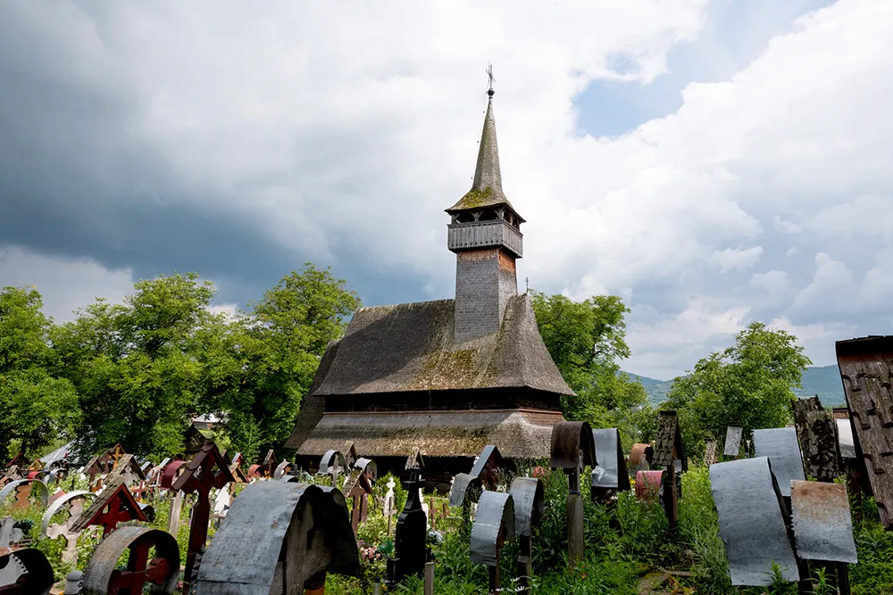 Ieud Hill Church and its graveyard, the oldest wood church in Maramures, Romania under a dramatic sky. The Church belongs to a collection of Wooden Churches of Maramures, UNESCO World Heritage Site.