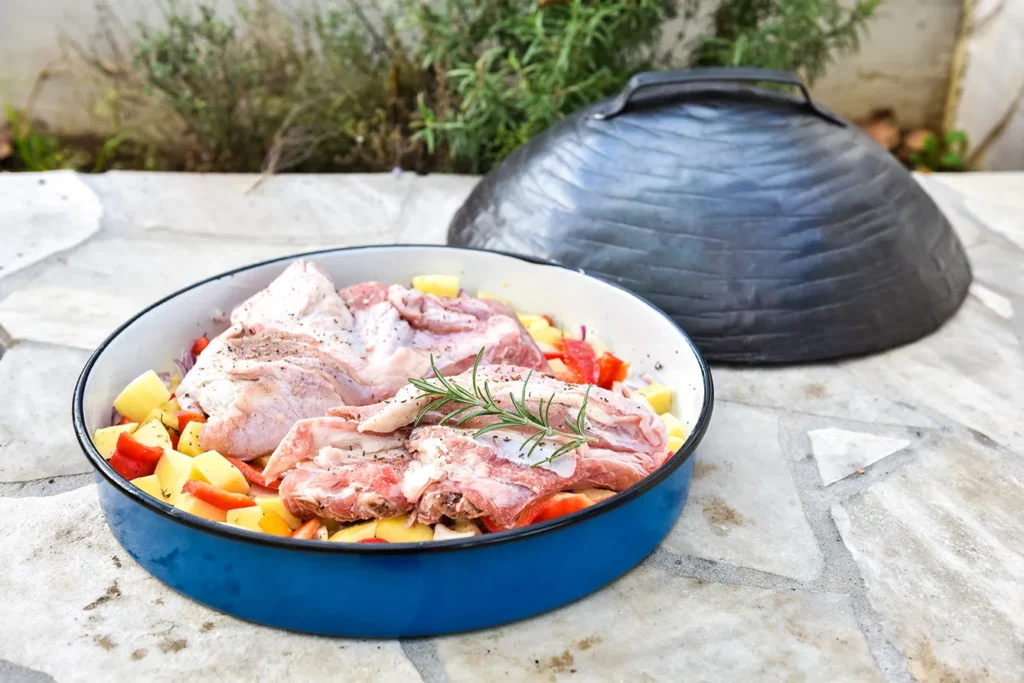 Cooking of traditional dalmatian meal Peka in metal pots called sac sach or sache. Traditional roast of pork beef or veal. Soft focus - shallow depth of field