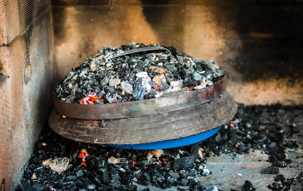 Cooking of traditional Mediterranean Croatian meal Peka in metal pots called sac sach or sache or a metal lid. Fireplace with open fire and burning coals