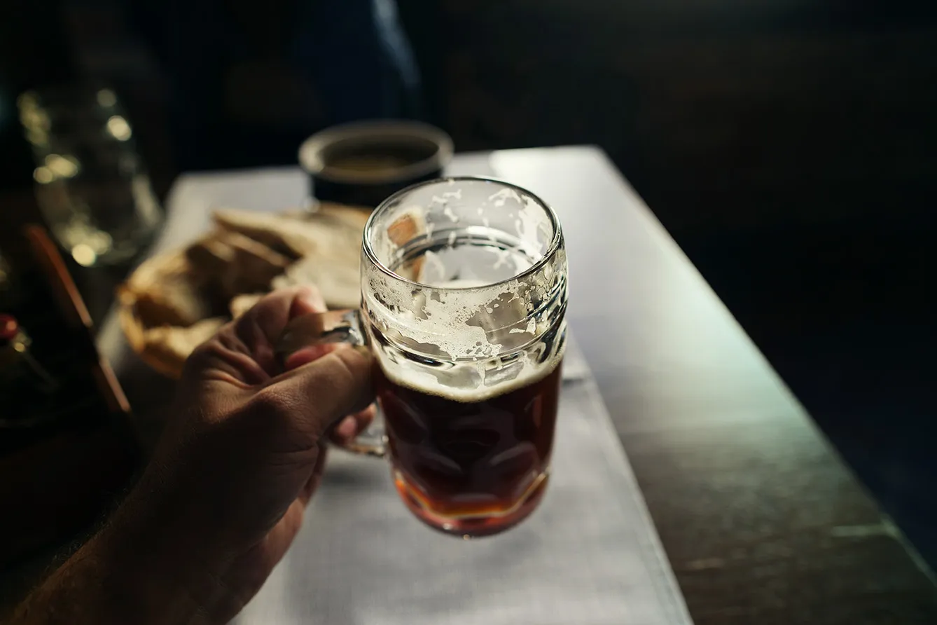 Glass of fresh dark podpiwek in male hand close up