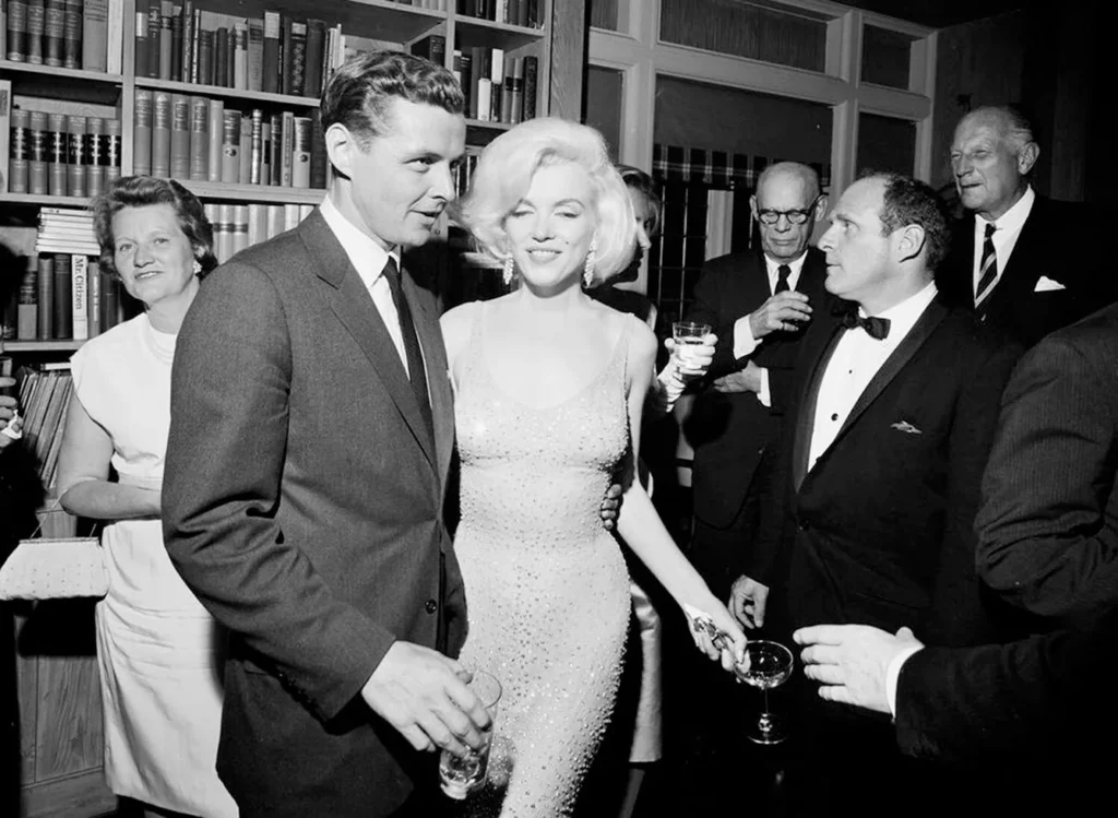 In this May 19, 1962 photo provided by the John F. Kennedy Presidential Library and Museum, actress Marilyn Monroe wears the iconic gown that she wore while singing "Happy Birthday" to President John F. Kennedy at Madison Square Garden, during a reception in New York City. Standing next to Monroe is Steve Smith, President Kennedy's brother-in-law.