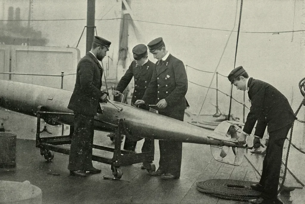 Torpedo instruction on board HMS 'Theseus', 1896. Four sailors with a Whitehead torpedo. The 'Theseus' was a cruiser launched in 1892. The self-propelled torpedo was invented by Robert Whitehead, a British engineer, in 1866. A print from The Navy and Army Illustrated, 12th June 1896.