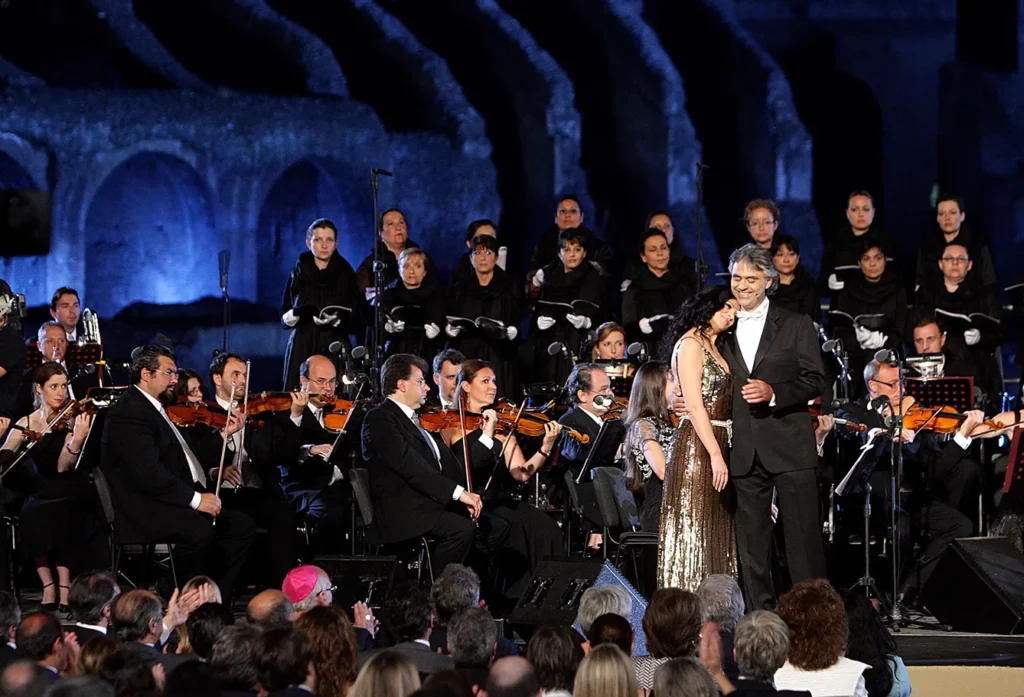 Andrea Bocelli Performs In Aid Of Earthquake Victims. Italian tenor Andrea Bocelli and opera star Angela Gheorghiu perform at the Colosseum in aid of earthquake victims on May 25, 2009 in Rome, Italy.