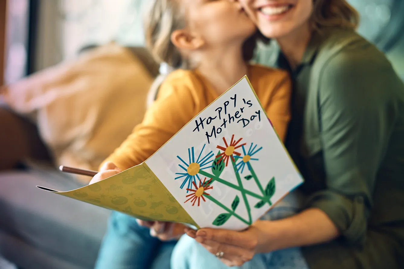 Close-up of woman receiving greeting card from her daughter on Mother's day.