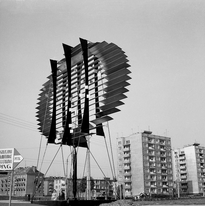 Elblag, 1965, Composition by Jerzy Jarnuszkiewicz, the sculpture is sometimes titled in two ways; once as "Signpost Composition," and at other times as "Greeting Sign." It emanates primarily from the play of chiaroscuro, built by appropriately angled sheets of metal resembling louvers. The form was renovated in 2006.