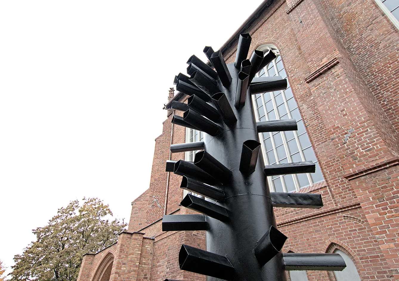 The sculpture by Magdalena Abakanowicz, is a tall, 7-meter composition, created from a rolled sheet of metal, on the outside of which the author placed short, polygonal in cross-section pipes. The whole suggests associations with a tree branch. Currently, Magdalena Abakanowicz's sculpture can be seen at the intersection of Przymurze and Przy Bramie Targowej streets, near the building of the High School.