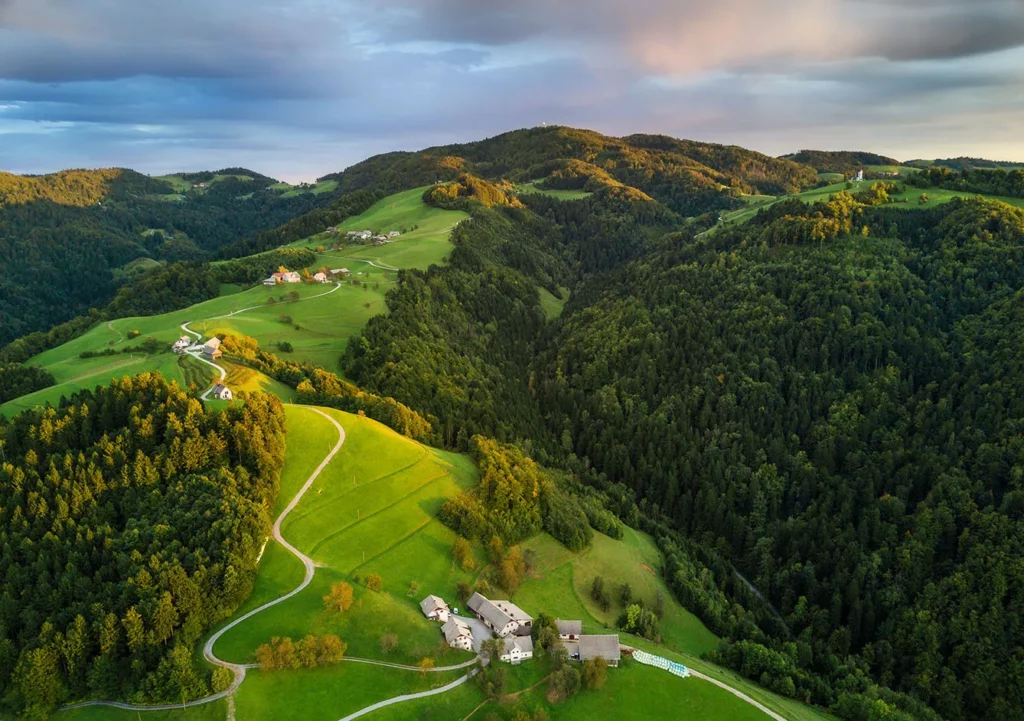 Aerial shot of green hills of Slovenia at sunrise.