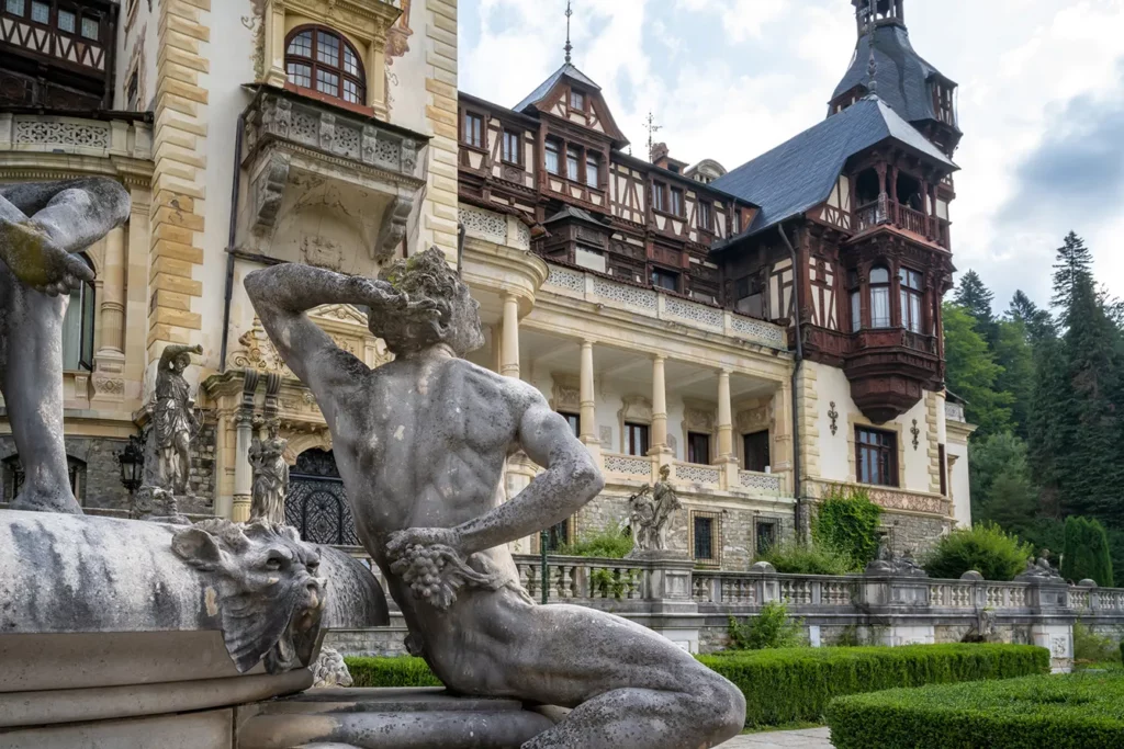 Sculptures and plants in garden in front of the facade of Peles Castle near. Photo: iStock.com / jk78