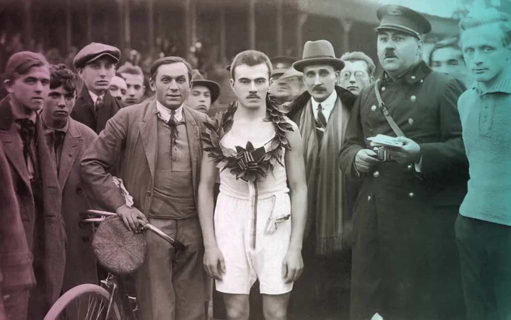 1924 - Karol Hala the first winner of the Peace Marathon stands surrounded by people posing for the camera.