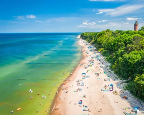 Crowded beach with people at Baltic Sea. Tourism on sea in Poland. Aerial view of nature.