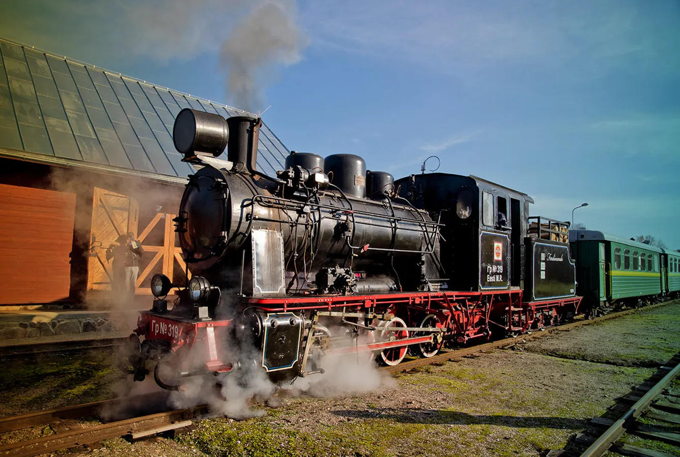 A steam locomotive pulls away from the station.