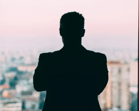Sillouette of a businessman looking at the view outside his office.