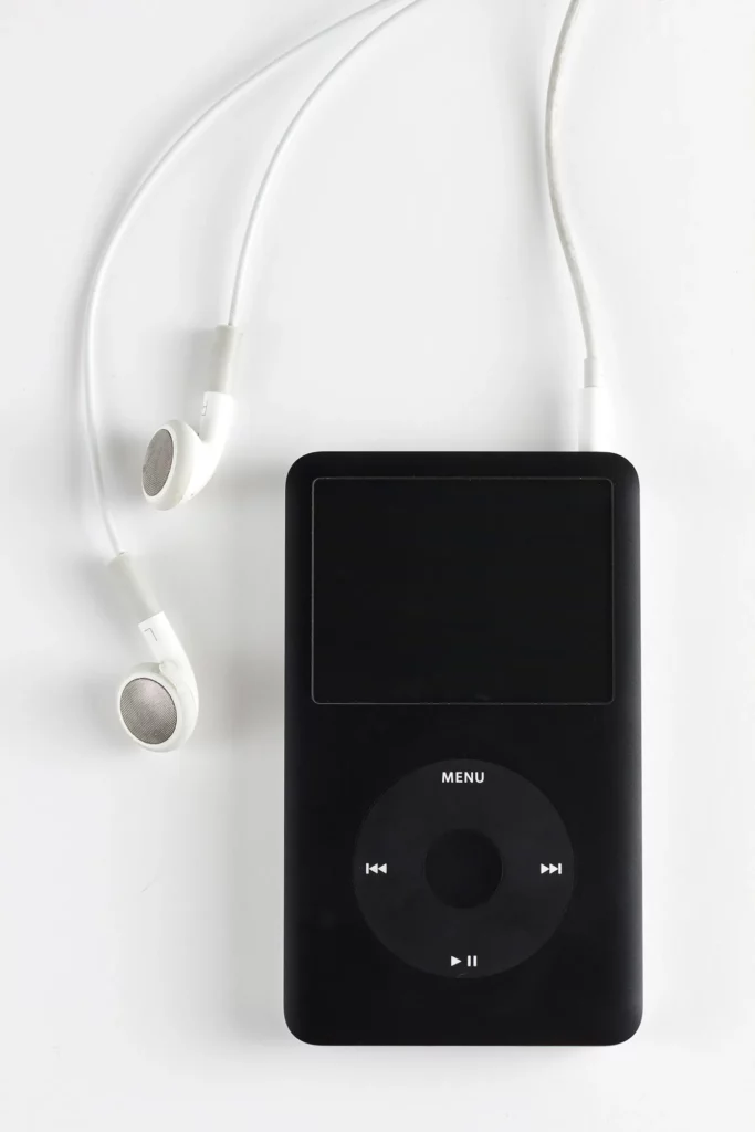 Close up on an Apple iPod resting on a white background, headphones are also visible in the frame.